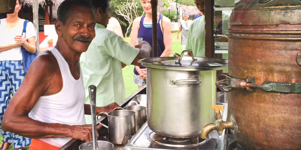 a man in a white top and orange bottom cooking